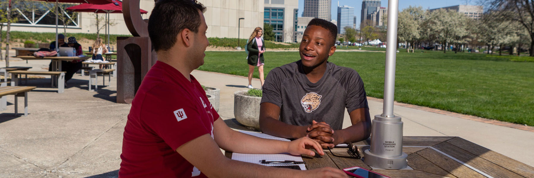 Two students talking at a table outside